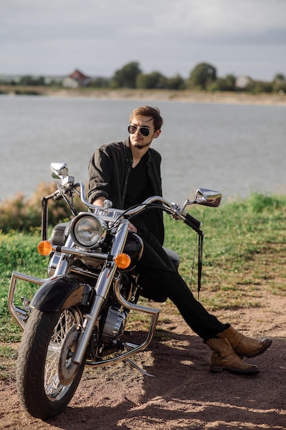 Handsome man or young biker sitting and chilling on the bike chopper outdoors