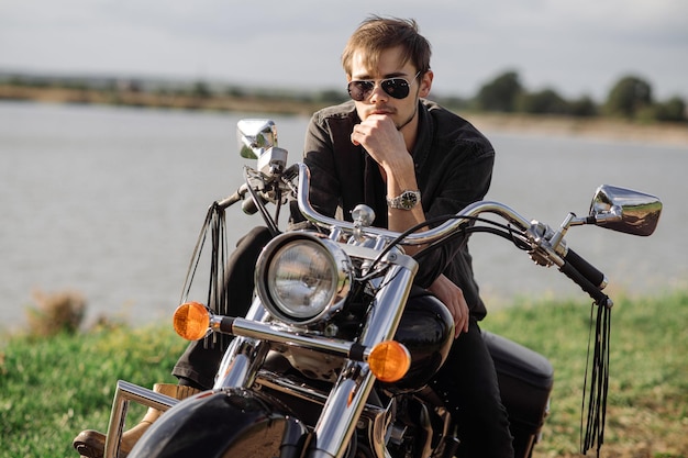 Handsome man or young biker sitting and chilling on the bike\
chopper outdoors