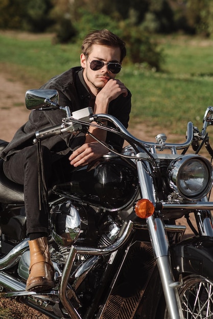 Handsome man or young biker sitting and chilling on the bike chopper outdoors