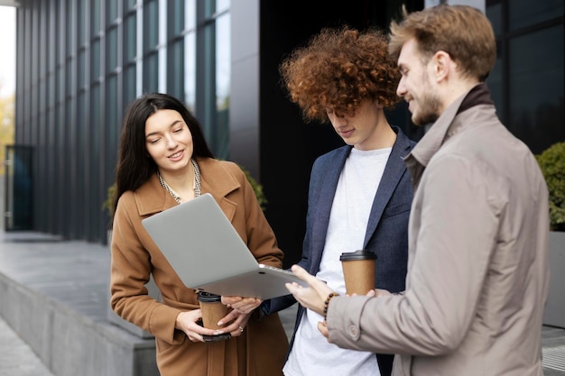 Bei manager che utilizzano un computer portatile che comunica bevendo caffè all'aperto vicino all'ufficio