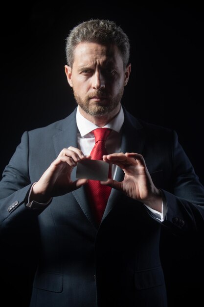 Handsome mature business man with credit card isolated on black background