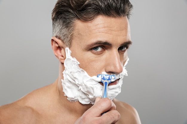 Photo handsome mature concentrated man naked shaving.