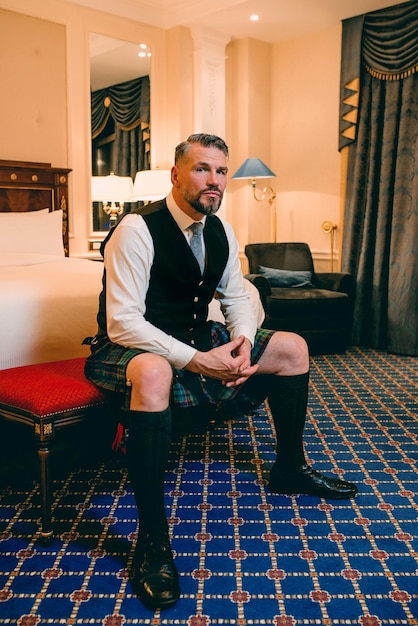 handsome mature courageous stylish man scotsman in kilt in fancy hotel room