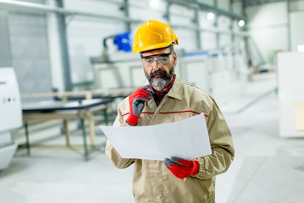 Handsome mature engineer looking at plan in the factory