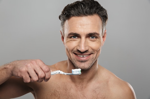 Handsome mature man brushing his teeth. 