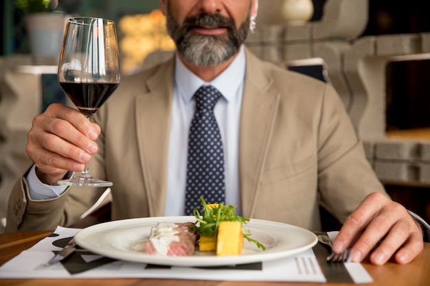 昼食時に赤ワインを飲むハンサムな中年の男性