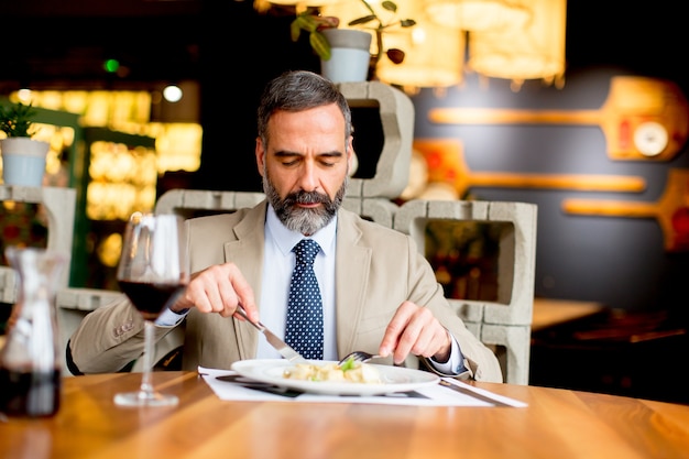 昼食の間に赤ワインを飲むハンサムな成熟した男