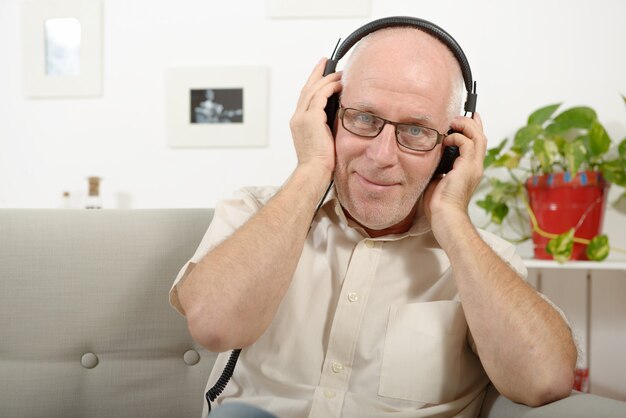 Красивый зрелый человек слушает музыку в наушниках