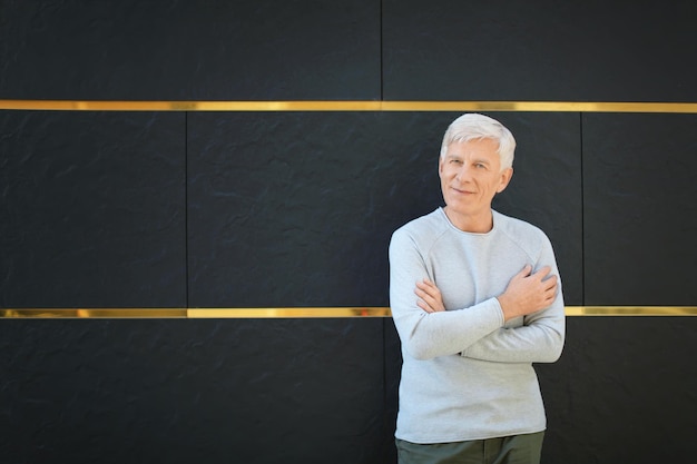 Photo handsome mature man near dark wall outdoors