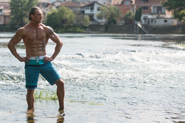 Handsome Mature Man Standing Strong Outdoors In Nature And Flexing Muscles  Muscular Athletic Bodybuilder Fitness Model Posing After Exercises