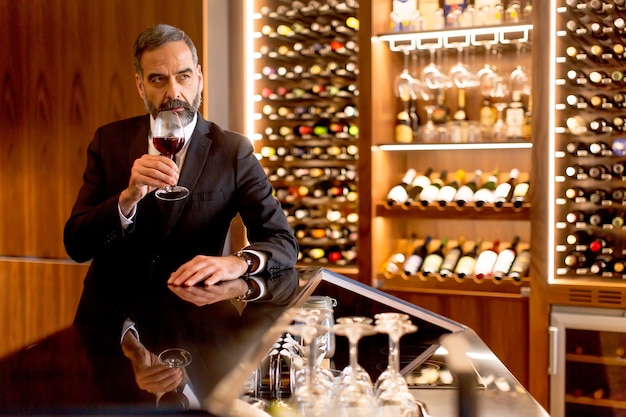 Handsome mature man tasting glass of red wine