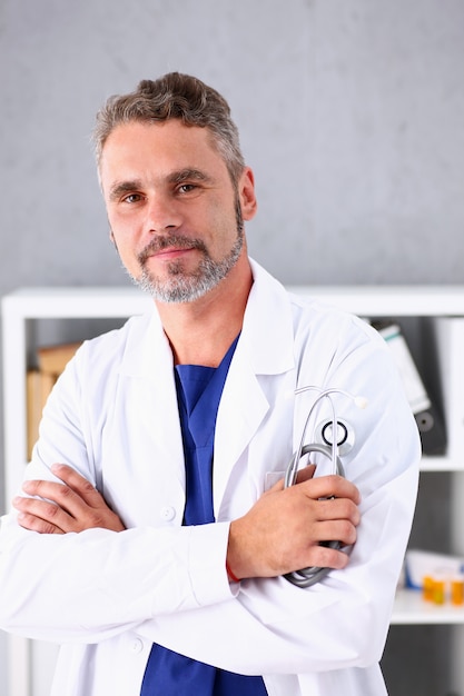 Handsome mature smiling male doctor with arms crossed on chest