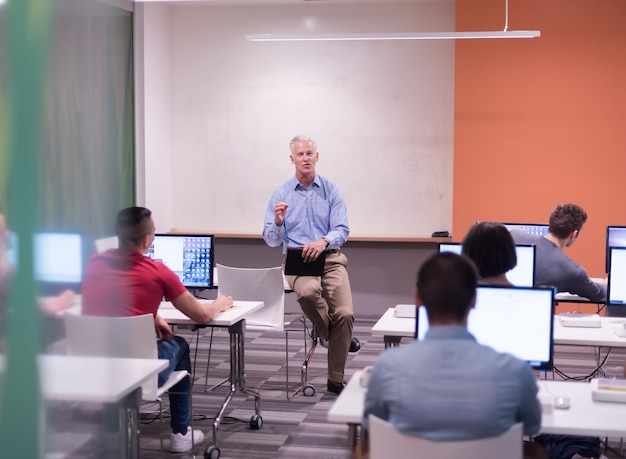 handsome mature teacher and students in computer lab classroom