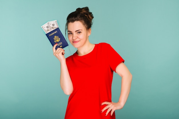 A handsome mature woman holding a passport with money dollars on a blue background - image