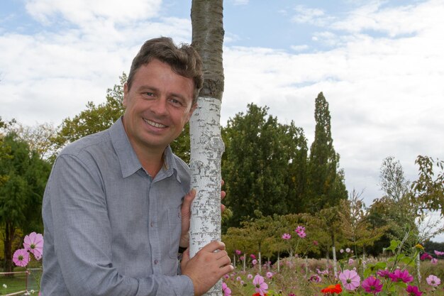 Handsome middle age man outdoor smiling leaning on tree