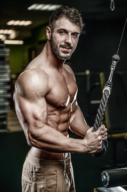 Handsome model young man training arms in gym