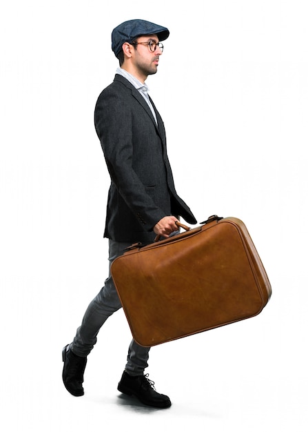 Handsome modern man with beret and glasses walking and holding a vintage briefcase