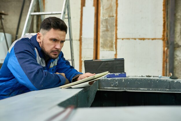 Uomo moderno bello che lavora nell'officina della barca