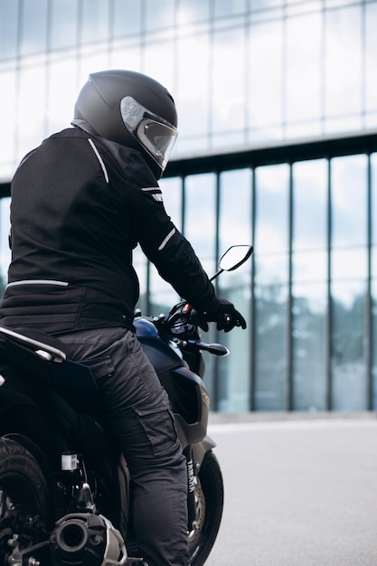 Handsome motorcyclist on his moto riding in the city