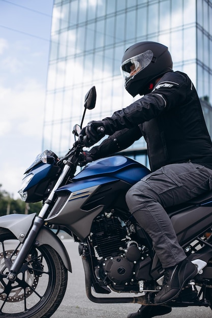 Handsome motorcyclist on his moto riding in the city