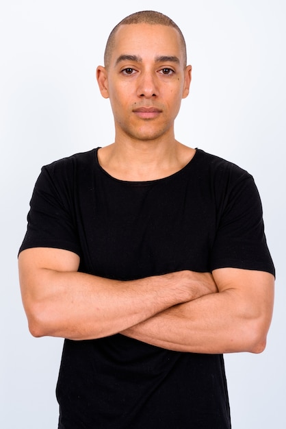 handsome multi ethnic bald man wearing black shirt against white wall