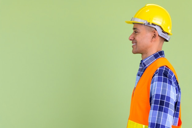  handsome multi ethnic man construction worker against colored wall