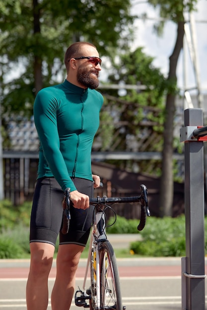 Фото Красивый мускулистый велосипедист, стоящий с велосипедом