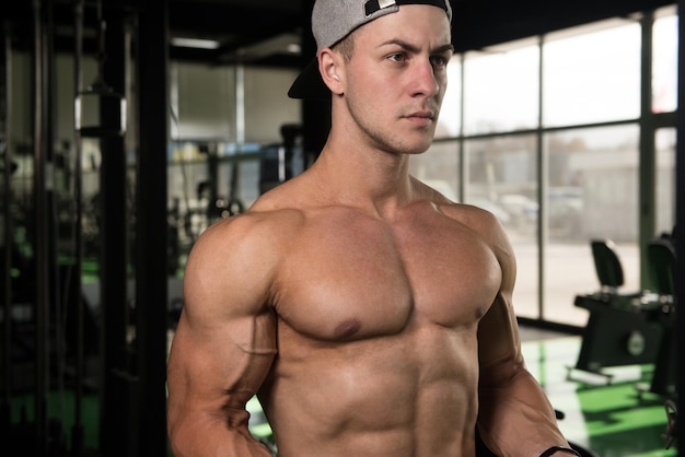 Handsome Muscular Fitness Bodybuilder Doing Heavy Weight Exercise For Biceps On Machine With Cable In The Gym