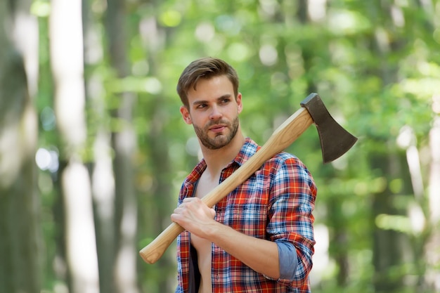 Handsome and muscular lumberjack man with an axe, camping.