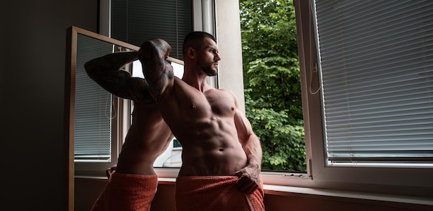 Handsome muscular man in bedroom on window curtains young handsome sexy man resting at home guy with