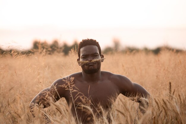 Handsome muscular man posing on rye field background