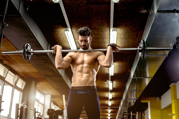 Handsome muscular man working out at gym.