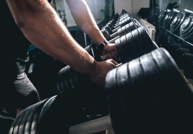 Handsome muscular man working out with dumbbells.