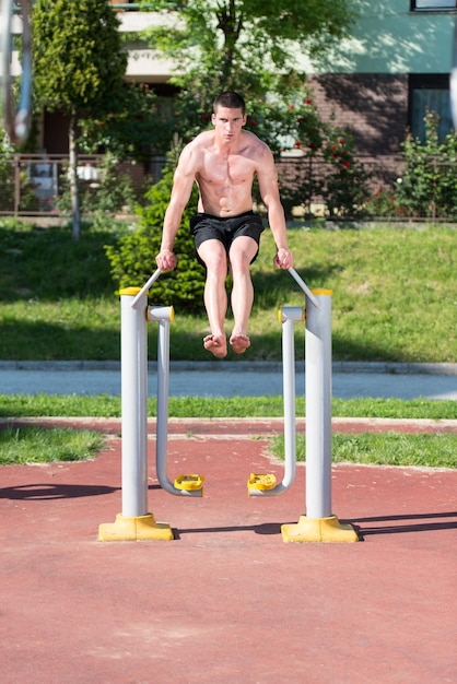 公園でハンサムな筋肉の若い男のトレーニング