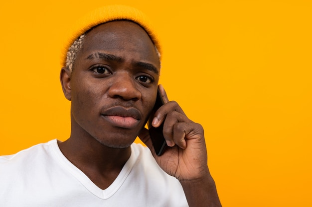 Handsome pensive serious american man talking on the phone on yellow