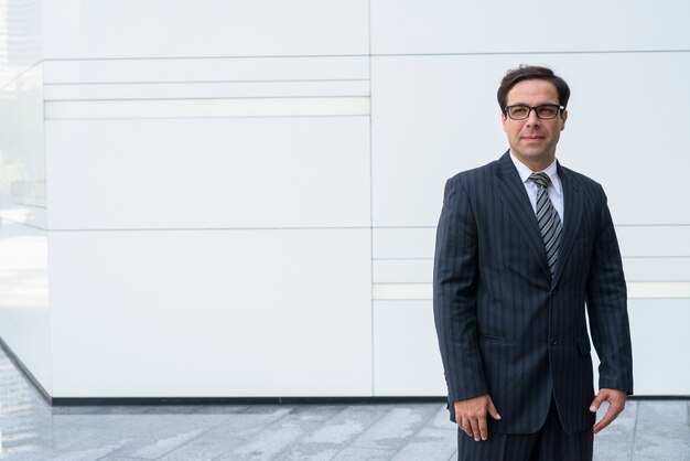 Handsome Persian businessman posing in front of white wall