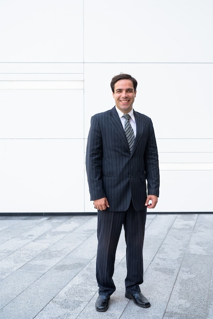 Handsome Persian businessman posing in front of white wall