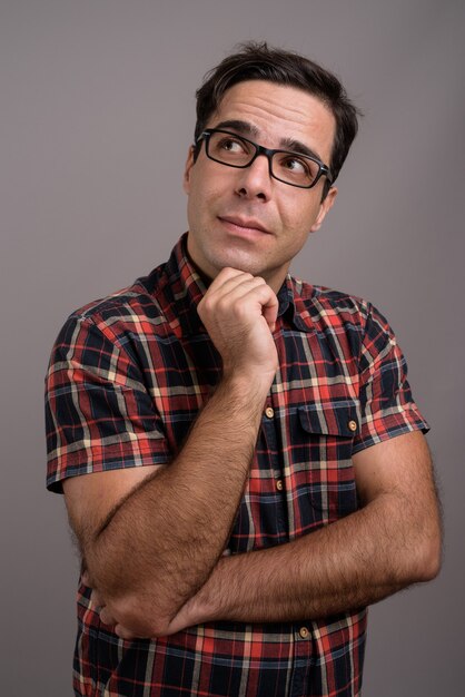 Handsome Persian man wearing eyeglasses against gray wall