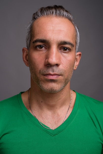 Handsome Persian man with gray hair wearing green t-shirt