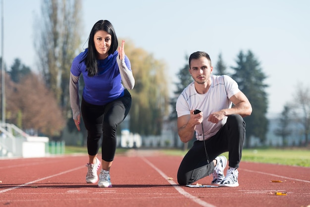 Handsome Personal Trainer Helping Woman To Sprint on the Running Track in City Park Area  Training and Exercising for Endurance  Healthy Lifestyle Concept Outdoor