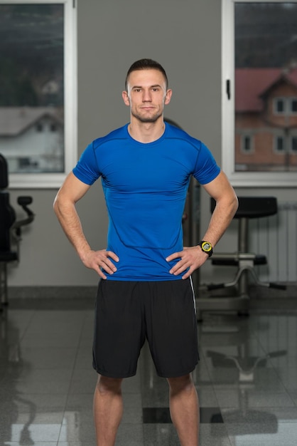 Foto bello personal trainer che indossa abbigliamento sportivo nel centro fitness