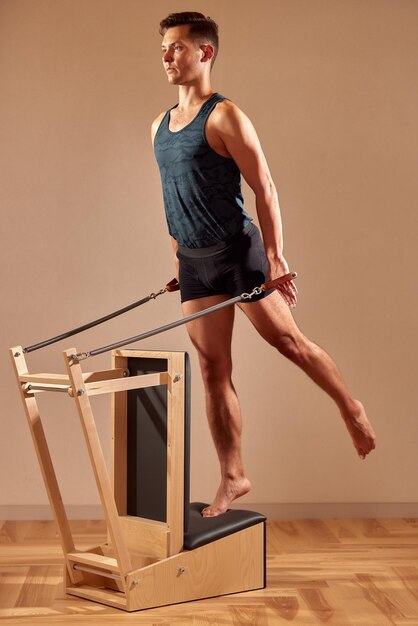 사진 필라테스 스튜디오 모던 실내 실내에서 작은 통 장비로 스트레칭 균형 운동을 하는 잘생긴 필라테스 남성 강사