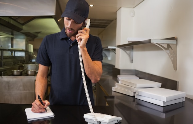 Foto fattorino della pizza bello che prende un ordine per telefono