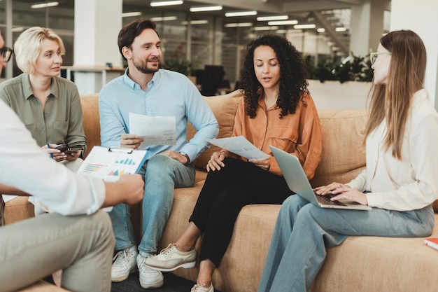 handsome positive business team sitting working with documents using laptop in modern office