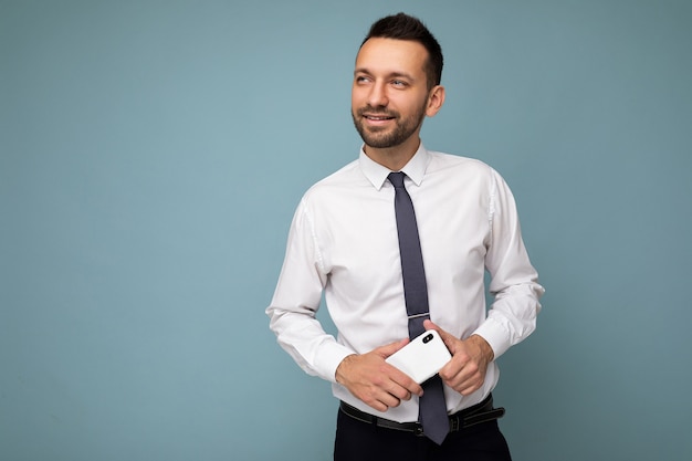 Handsome positive thoughtful good looking brunet unshaven man with beard wearing casual white shirt