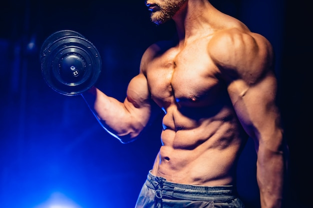 Handsome power athletic man bodybuilder doing exercises with dumbbell.