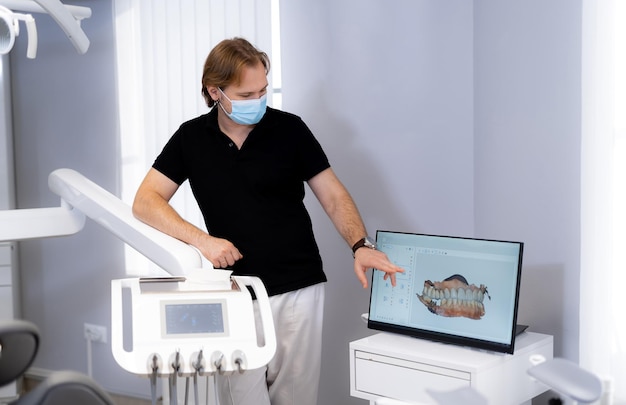 Handsome professional dentist working with display. Teeth healthcare specialist with new technology.