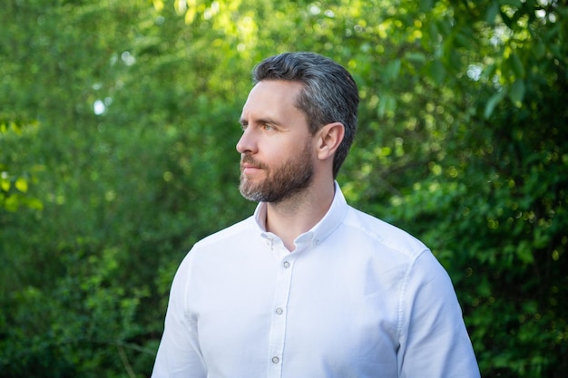 Handsome professional guy in white shirt looking aside natural background