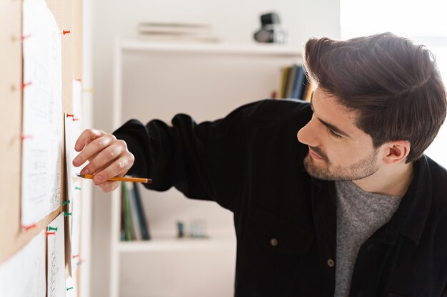 机の上のプロジェクトで事務作業のハンサムなプロの男性建築家。