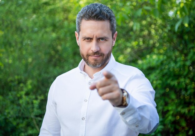 Handsome professional man selective focus pointing finger natural background